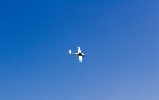 Ultra light, cessna plane from above with prolonge rope on blue sky. Sport, transportation background