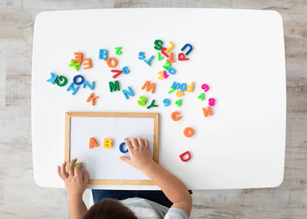 corsi di lingua straniera. vista dall'alto del bambino che fa nota abc con lettere inglesi colorate, vista dall'alto, spazio vuoto - reading and writing classroom alphabet learning foto e immagini stock