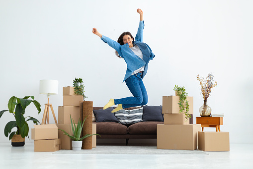 Young happy woman is beside herself with moving to her new house or apartment. Funny female jumping for happiness after buying a new home. Rental housing