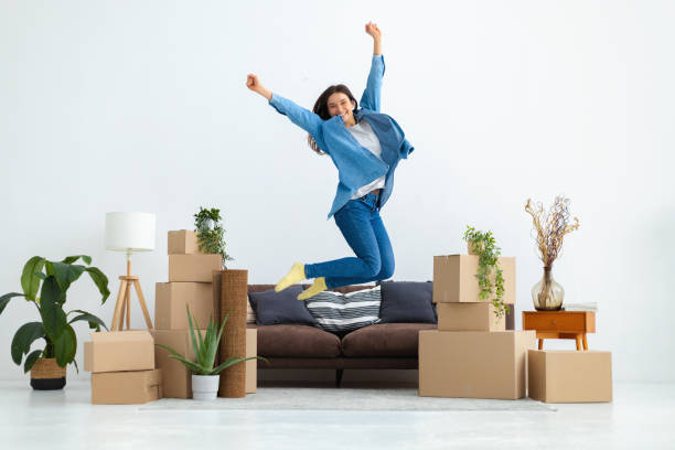 Young happy woman is beside herself with moving to her new house or apartment. Funny female jumping for happiness after buying a new home. Rental housing stock photo
