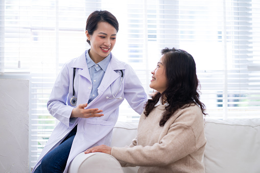 Asian female doctor examining an elderly woman at home