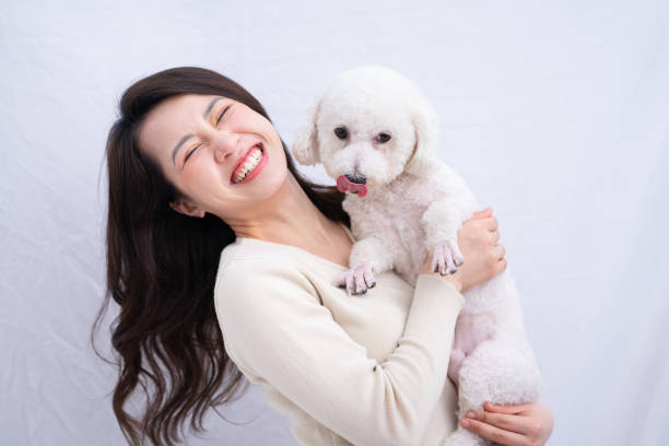Young Asian woman hugging her dog on white background