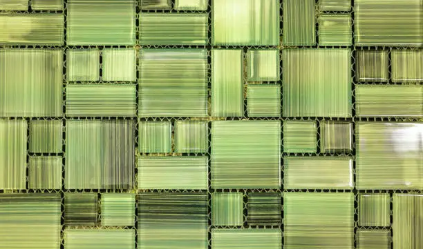 Photo of Abstract green background. Small green modern mosaic tile in bathroom. Transparent glass tiles wall background