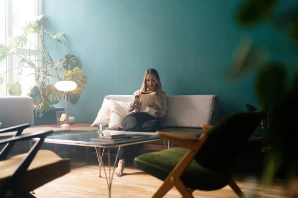 istock Woman reading a book on the sofa 1387950781