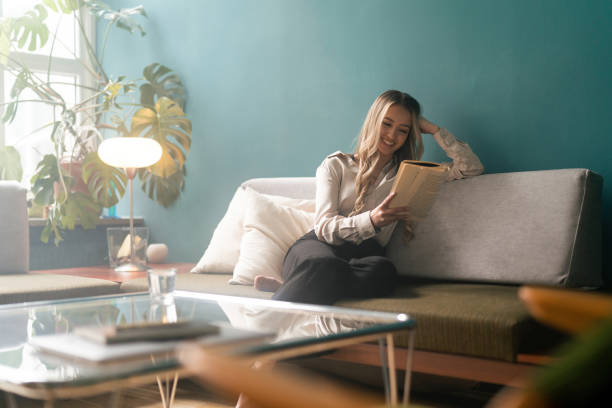 istock Woman reading a book on the sofa 1387950782