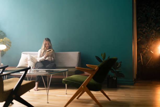 istock Woman reading a book on the sofa 1387950783