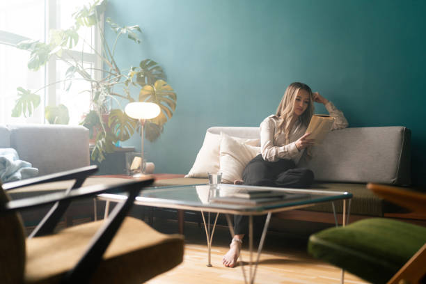istock Woman reading a book on the sofa 1387950785