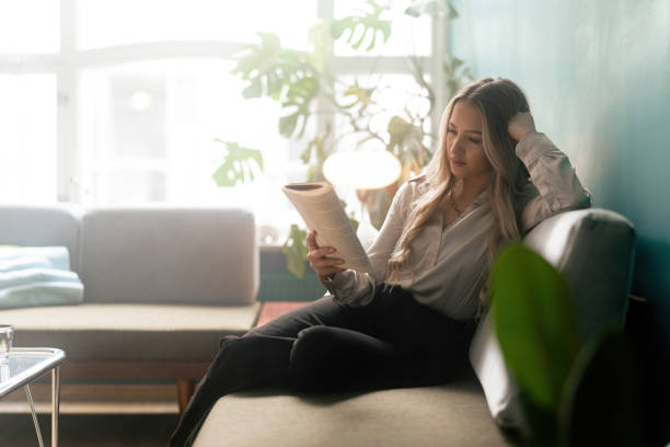 istock Woman reading a book on the sofa 1387950792