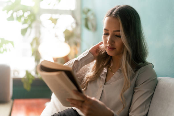 istock Woman reading a book on the sofa 1387950795