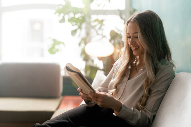 istock Woman reading a book on the sofa 1387950796