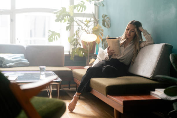 istock Woman reading a book on the sofa 1387950964