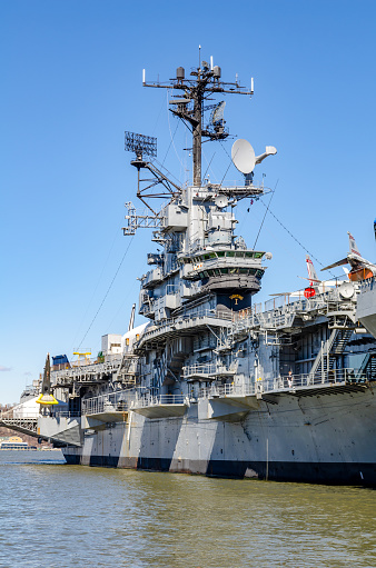 Intrepid Sea-Air-Space Museum with tower of the ship close-up at Hudson River side view, New York City during sunny winter day with clear sky, vertical