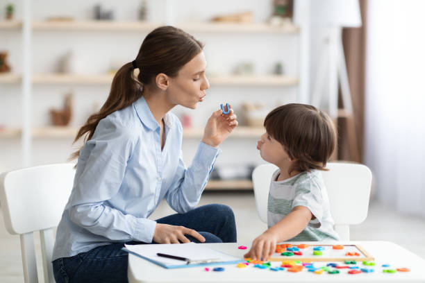 junge frau logopädin unterrichtet kleinen jungen mit aussprachedefikten, um während des trainings gesundes u zu sagen - child speech therapy adult stock-fotos und bilder