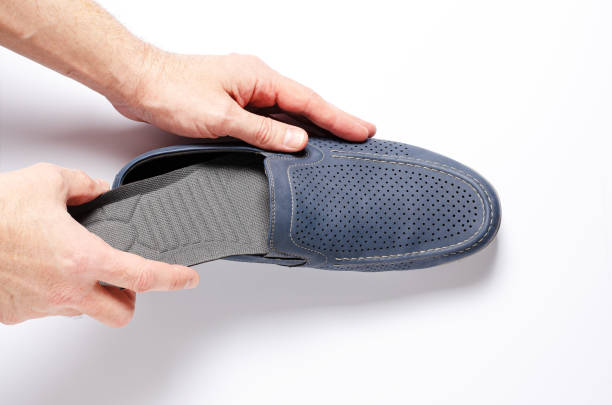 istock A man changes the insole in his shoes. White background, closeup. 1387958171