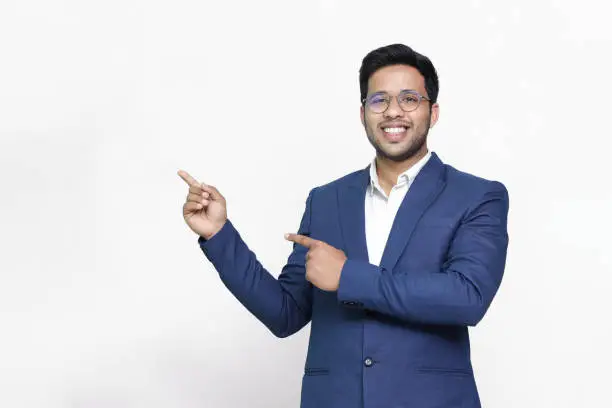 Portrait of a happy businessman pointing finger away over white background.