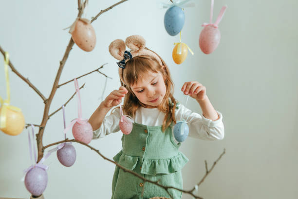 istock Little girl decorating a tree with Easter eggs indoor 1387963646