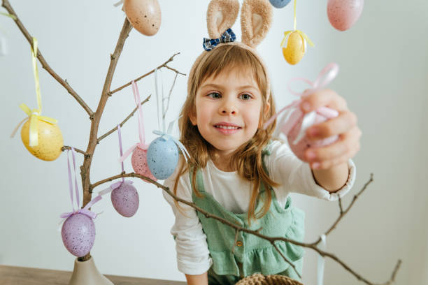 istock Little girl decorating a tree with Easter eggs indoor 1387963659