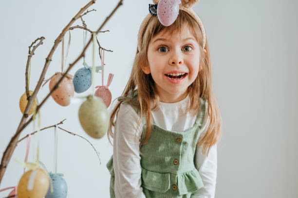 istock Little girl decorating a tree with Easter eggs indoor 1387963729