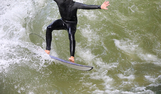 athlete does surf balancing on the surfboard on the river in the city of munich in Germany