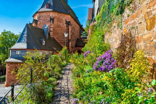 The "Kugelkirche" in the historic old town of Marburg an der Lahn with a footpath framed by flowers