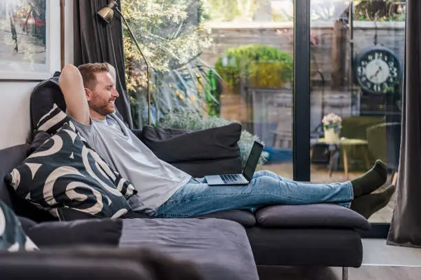 Photo of Calm caucasian man, watching a series, relaxing at home.