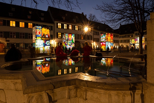Basel, Switzerland - February 23, 2021. Carnival revellers in red costumes at the fountain on the cathedral square