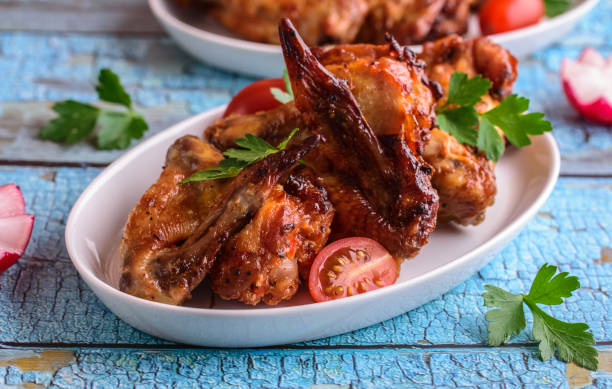 istock Baked crispy chicken wings in a white plate on a blue background. 1387968257