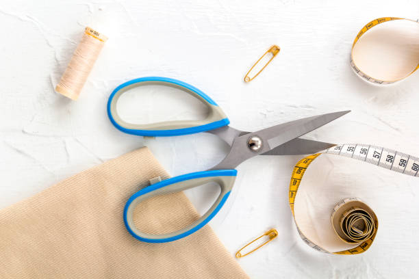 istock Opened scissors, tailor's tape measure, threads and pins on a white background. Top view 1387968492