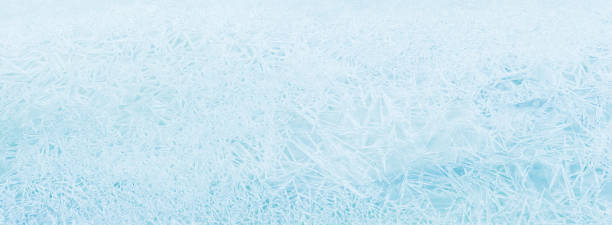 istock Natural ice panoramic background. Texture frozen natural blue ice crystals, top view. Ice patterns on the water surface winter 1387969336