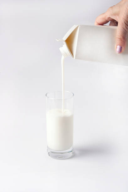 istock female hand pours yogurt from a box into a glass, mockup, copy space 1387969564