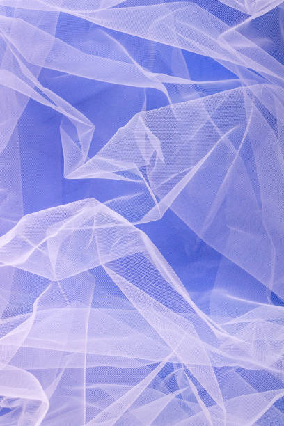 istock sheer tulle fabric arranged in soft folds on a blue background, selective focus 1387970159