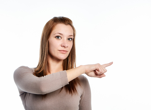 Young woman pointing at something to her left.