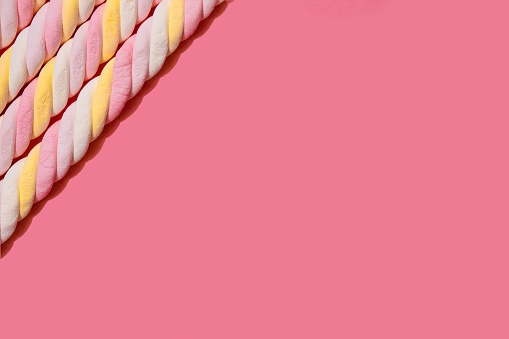 Border of spiral marshmallows on a pink background. Copy space. Top view