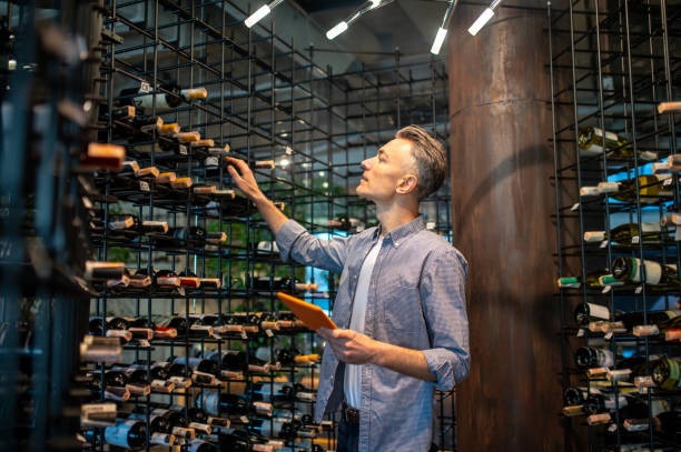 il proprietario di un'enoteca fa una revisione e sembra occupato - liquor store foto e immagini stock