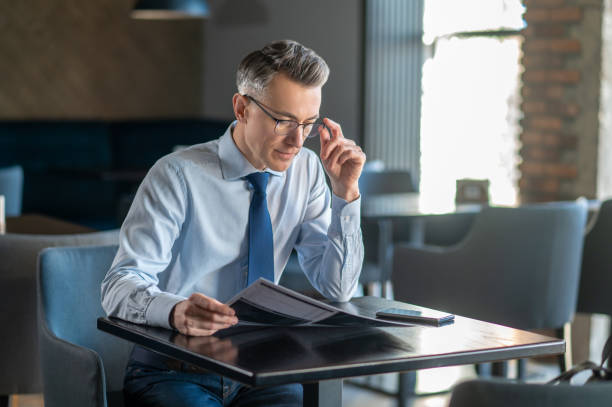 istock Mid aged man in elegant clothes sitting at the table in a cafe 1387978641
