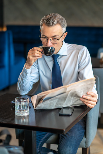 Reading news. A businessman reading newspaper in a cafe