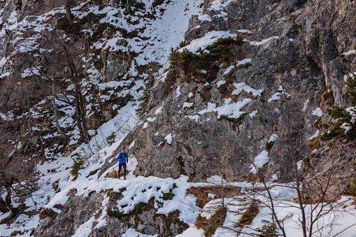 A well active, athletic Caucasian trail runner running outside in winter mountains.