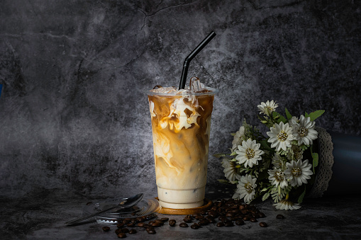 Thai coffee in a tall plastic cup There is steam next to the glass, cold.