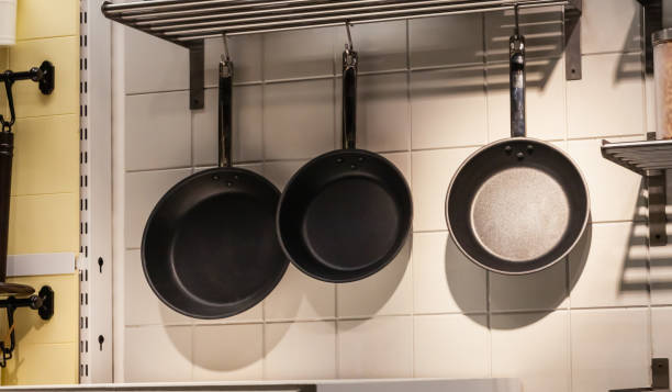 istock Kitchenware, pans, cutlery hanging in a row on a white brick wall 1387979744