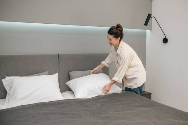 istock A young woman making bed and looking positive 1387979833