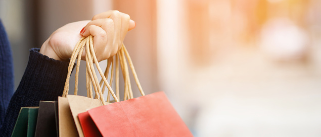 Close up of consumerism young woman holding hand many shopping bag in fashion boutique after buying presents while walking along the street with copy space , enjoying summer sale and people concept