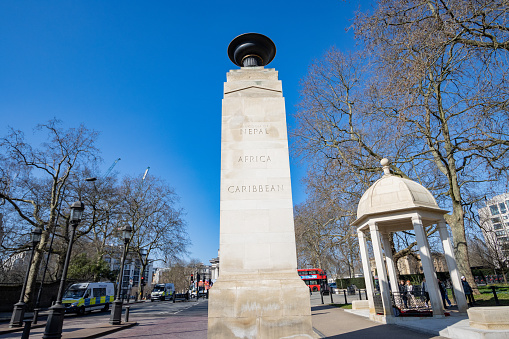 Stone Pillars of Memorial Gate on Constitution Hill in City of Westminster, London. People walk near the Memorial Gates which honour the 5 million people from Nepal, India, Africa and the Caribbean who fought for the armed forces in both world wars.