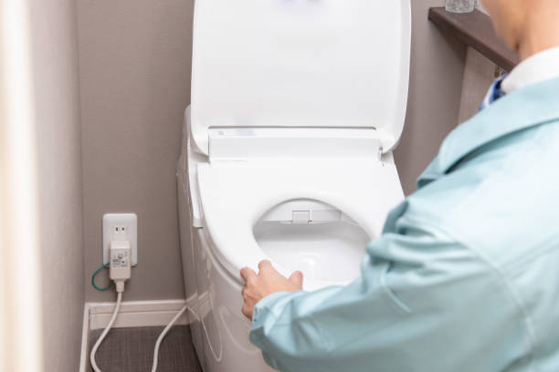 A man in work clothes checking the toilet A man in work clothes checking the toilet japanese toilet stock pictures, royalty-free photos & images