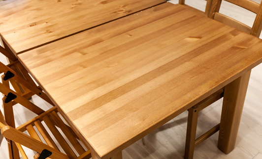 The table is covered with epoxy resin and varnished. Luxury quality wood processing. Wooden table on a concrete background. A black epoxy river in a rectangular tree slab.