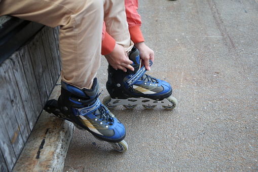 Focus on young woman's hands putting on inline skates.