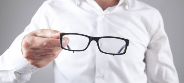 istock Man holding eyeglasses in office. 1387991523