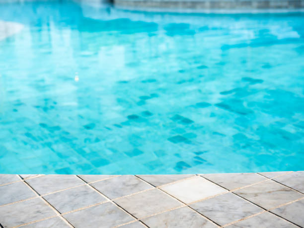 istock Summer pool background. Empty space on the pool edge, marble stone tiles and blurred swimming pool in tropical resort, summer background for display or montage your products. 1387992036
