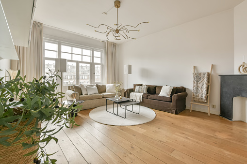 Living room with comfortable sofas on the parquet floor and access to the balcony in a modern house