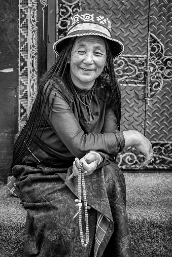 Unidentified tibetan pilgrim in traditional clothes sit nearby Jokhang temple with Tibetan mandala - Lhasa, Tibet