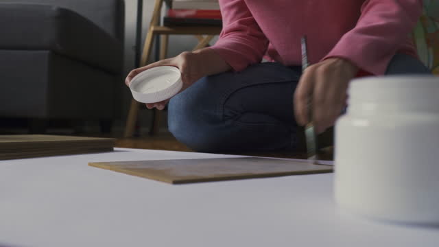 An artist primes canvas with white paint on paper at a drawing school